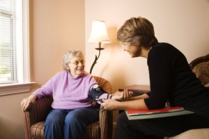 caregiver checking an elderly woman's blood pressure